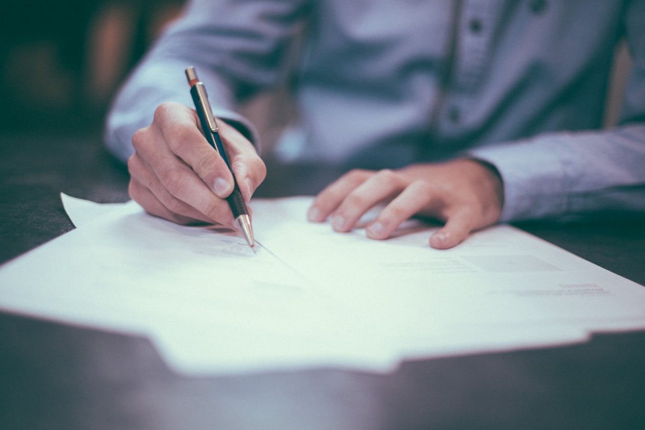 Close-up of hands marking up a printed document with a pencil, illustrating checking traffic data by hand before shifting any ad budget