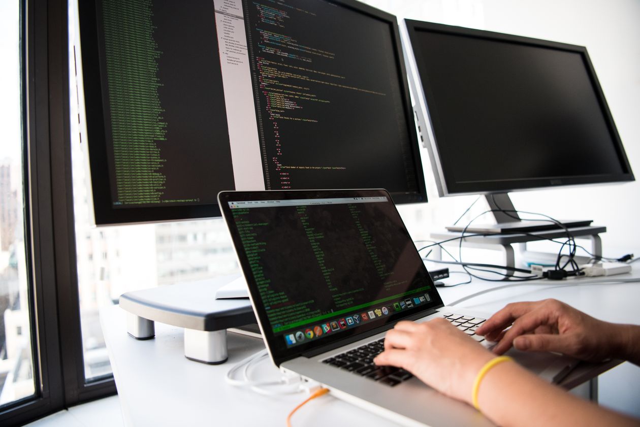 Hands typing on a laptop connected to external monitors displaying code, illustrating the developer-style setup behind an ads MCP server connection