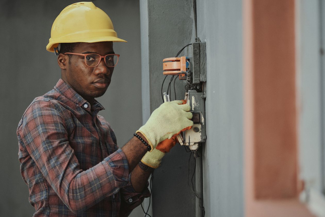 Electrician in a hard hat wiring an outdoor junction box with both hands occupied, illustrating why Local Services Ads calls go unanswered