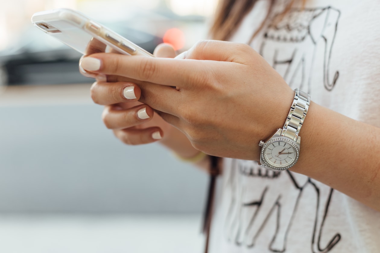 Close-up of a person's hands holding a smartphone on a city street mid-scroll, illustrating how little above-the-fold space a mobile search result now gets