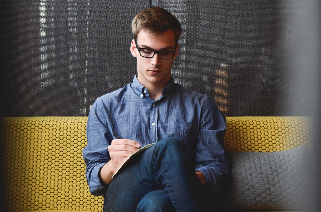 Founder sitting alone writing in a notebook by hand, illustrating the manual CPA math a solo advertiser should do before trusting a new column