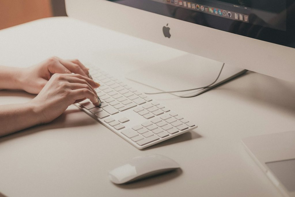 Hands typing a short query on a keyboard, illustrating the explicit typed intent that exact and phrase match keywords serve inside AI Mode