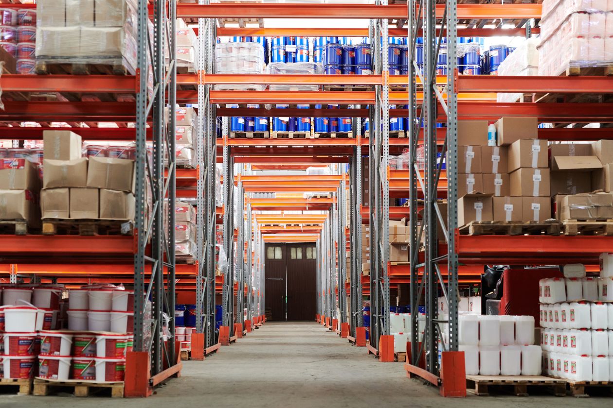 Warehouse aisle stacked with mixed inventory on tall orange racking, illustrating the SKU-level value choices behind Google Ads product value adjustments