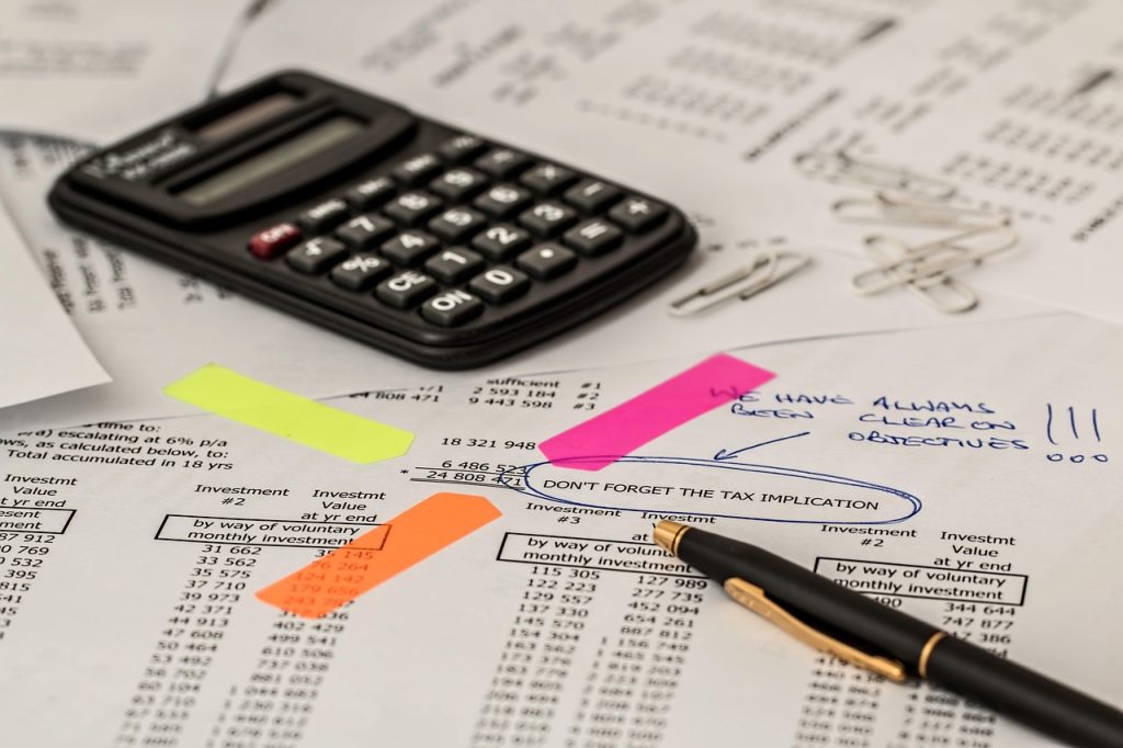 Pocket calculator and pen resting on a highlighted printed financial statement, illustrating the margin arithmetic a peer-spend benchmark leaves out