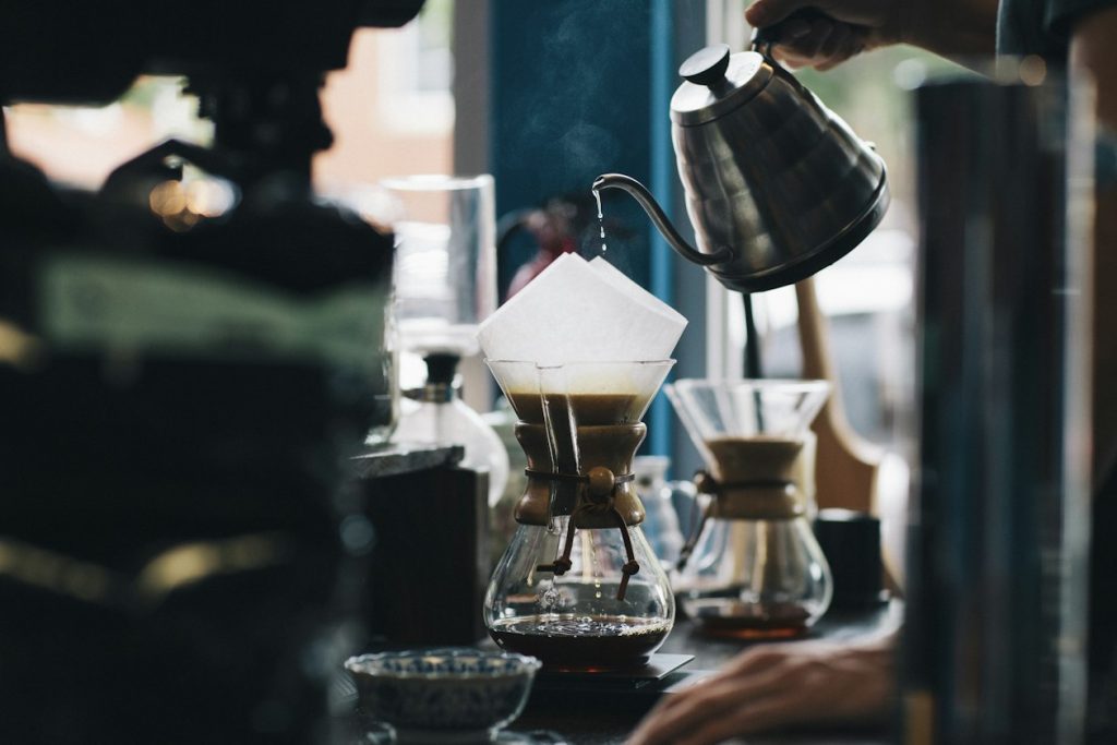 Barista pouring water from a gooseneck kettle into a pour-over coffee brewer, illustrating a small coffee brand deciding who its first-order ads should reach