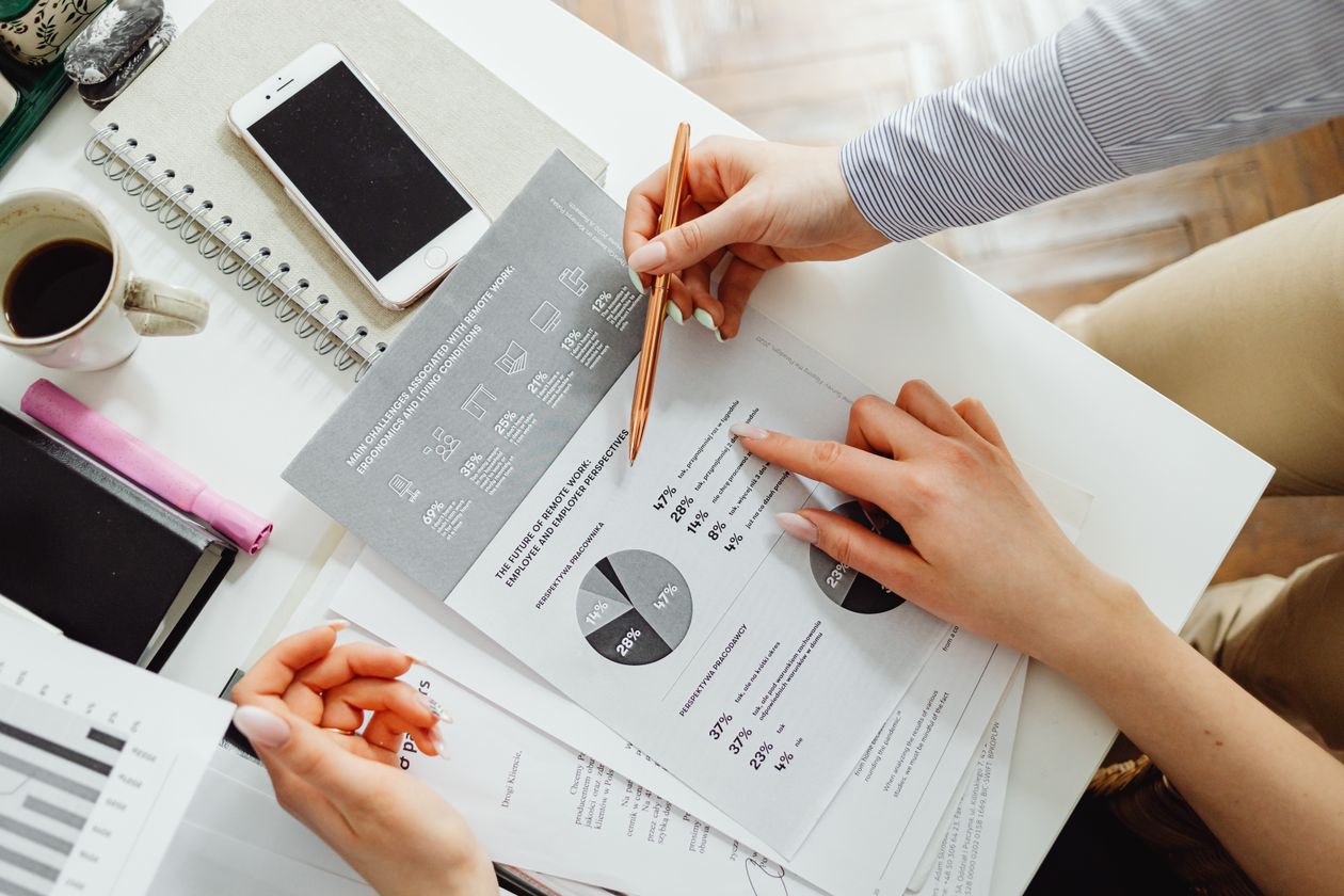 Two people reviewing a printed report with pie charts and a pen on a desk, illustrating how a small team reallocates ad budget between Google channels