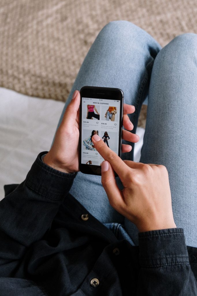 Close-up of a person scrolling a clothing shopping app on a smartphone, illustrating in-app product browsing after someone taps a Meta ad