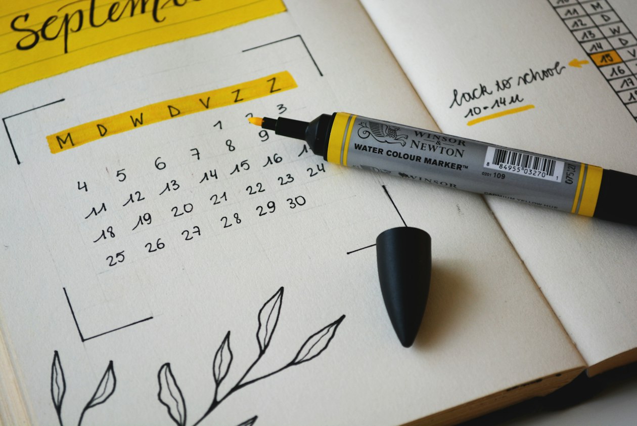 Hand-drawn monthly calendar in an open notebook with a marker, illustrating how LinkedIn weekly budget pacing drifts from a small team's monthly plan